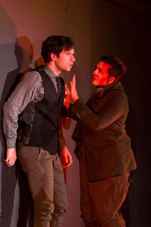 Mardonius in green corduroy jacket and pants holds his hands up to the distraught Arbaces in green vest, shirt, and slacks.